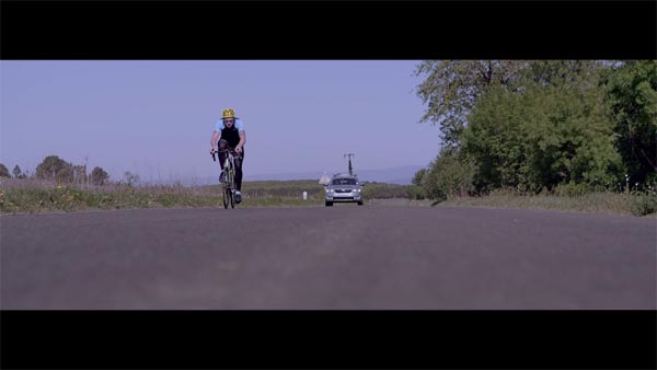 James Golding alone on the road, riding his bike to beat the record. A still from the documentation short film Distance Over Time.
