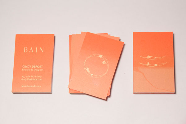Orange business cards with golden graphics and typography.