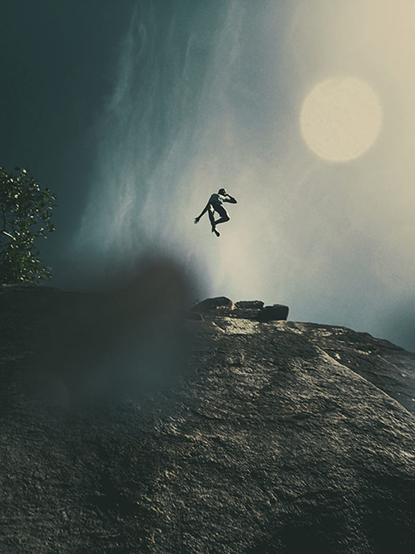 A boy is jumping from a steep cliff.