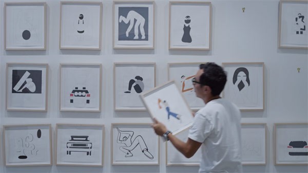 Geoff McFetridge in front of a collection of his paintings.