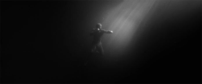 Amazing underwater scene showing the man free-floating in the water, boxing in a spotlight.