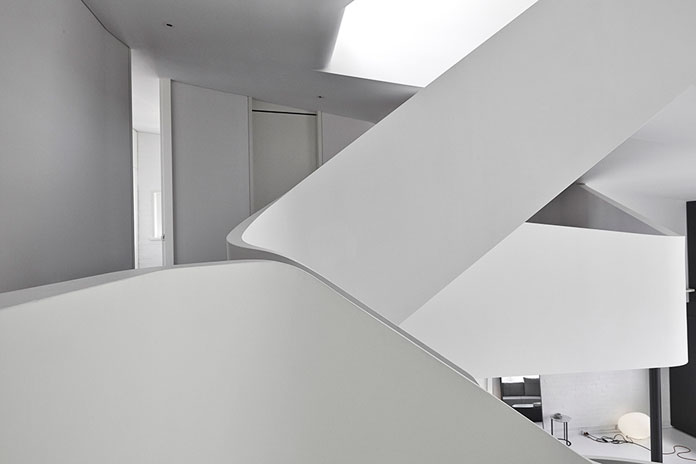 The space is characterized by the curvilinear forms of the staircase and the different floors.