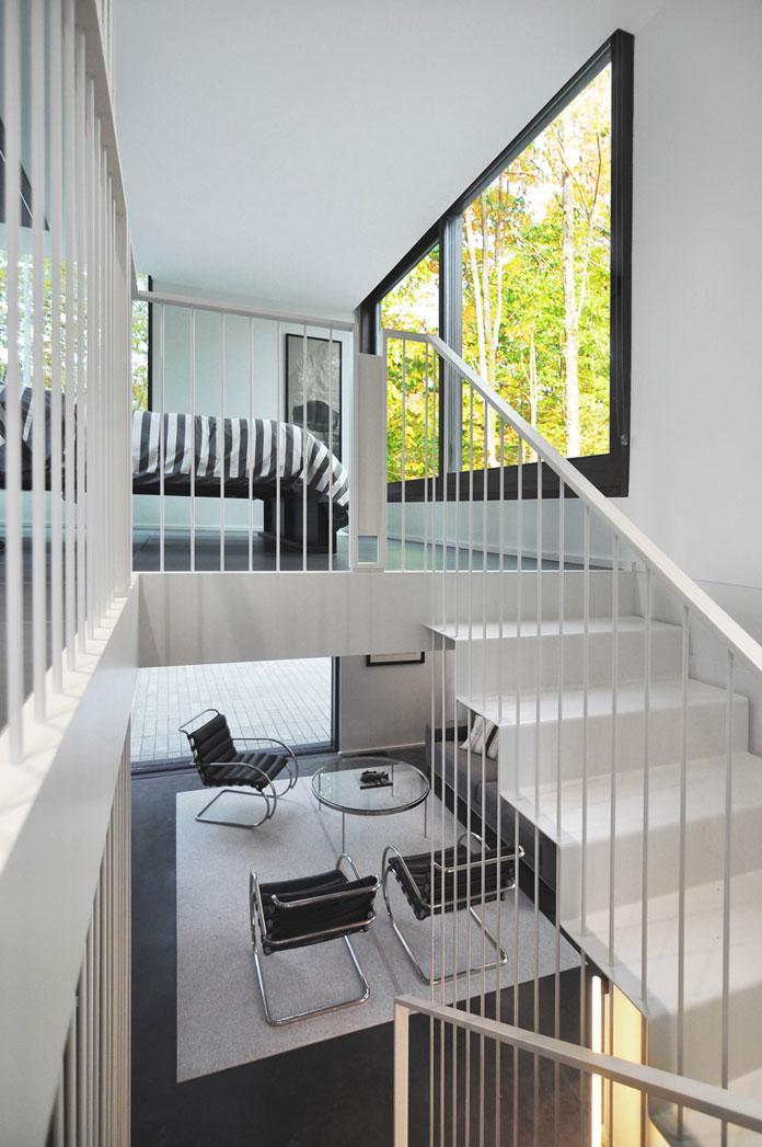 A steel staircase with vertical rods leads from the living area up to the bedroom.