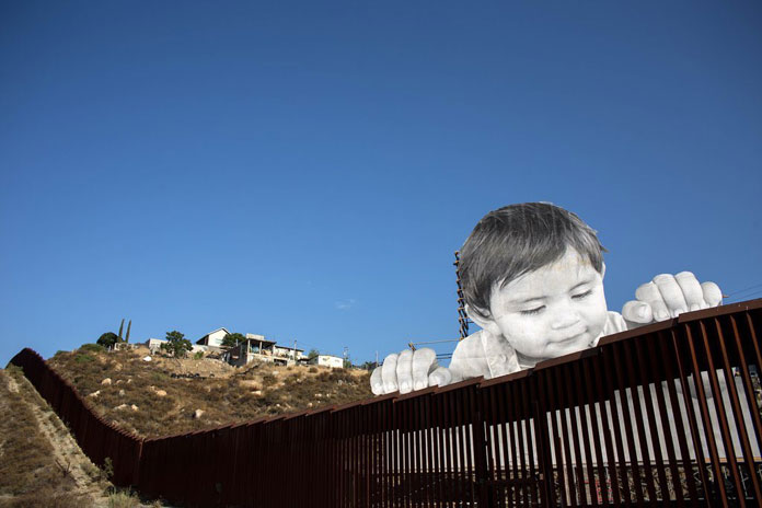 The nearly 70-ft tall image creates the illusion of a child that's looking over the frontier wall.