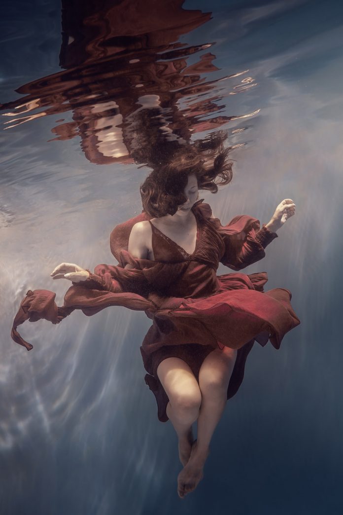 Photographie sous-marine d'art d'une jeune fille en robe rouge.